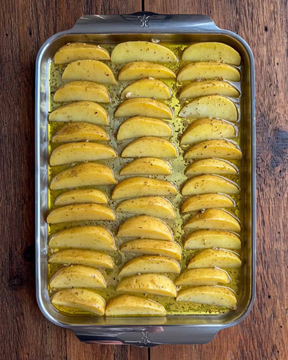 Sheet pan with three rows of lemon potato wedges.
