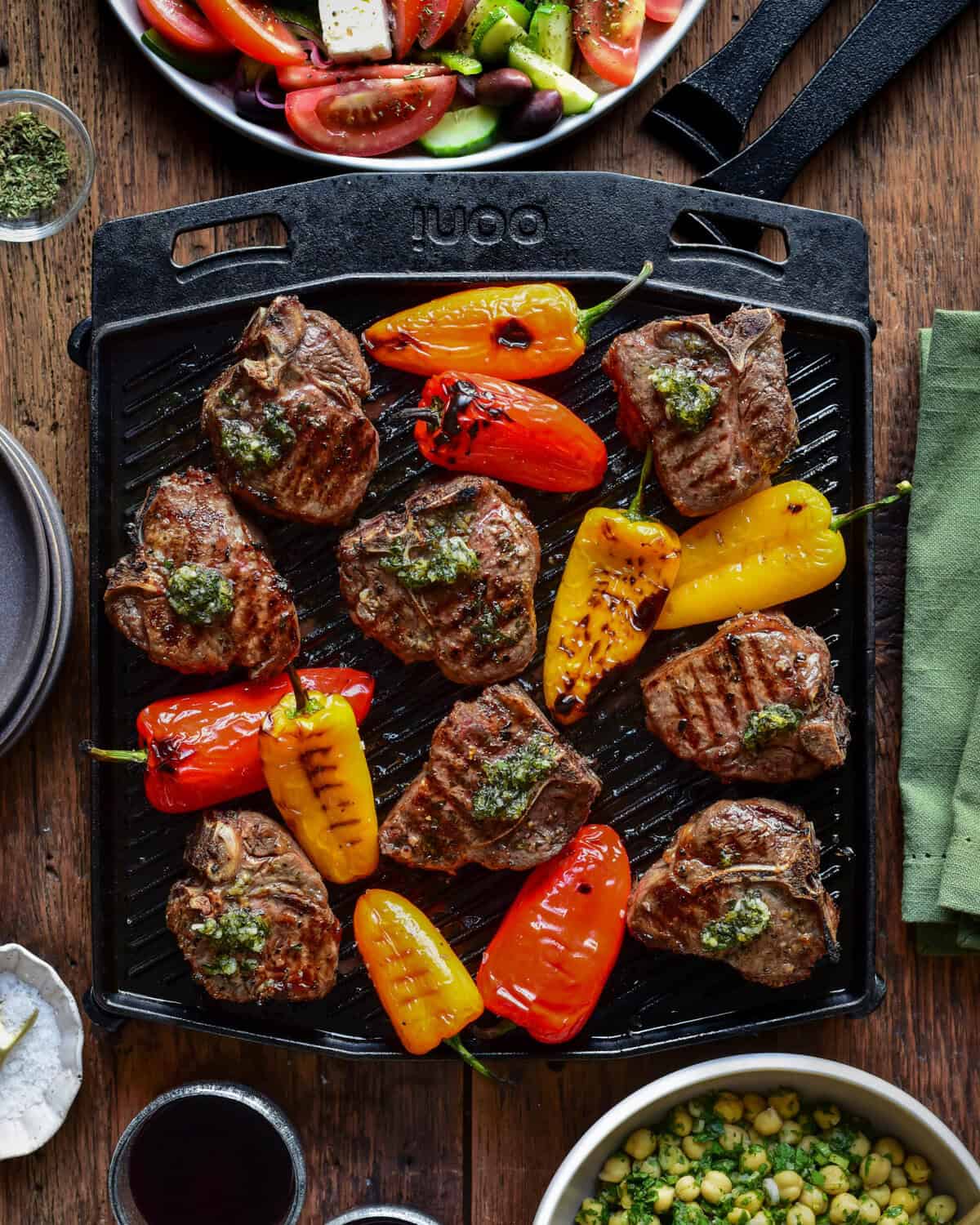 A cast iron skillet with Greek lamb chops and blistered peppers. 
