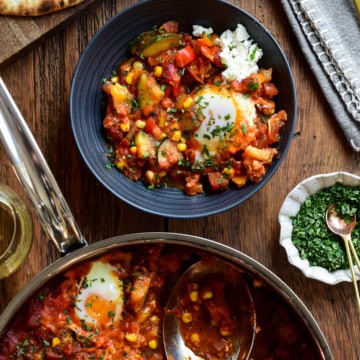 A serving of summer vegetable shakshuka with a baked egg and feta in a bowl.
