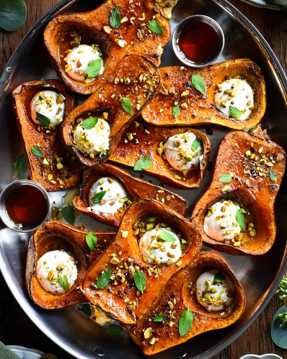 A platter of roasted Honeynut squash brulee topped with labneh, maple drizzle, mint and crushed pistachios.