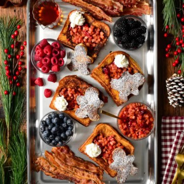 Gingerbread French Toast with Apple Cranberry Compote served with fresh berries and bacon. Topped with whipped cream and dusted with icing sugar.