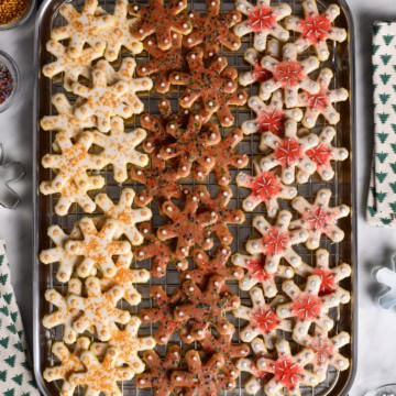 A baking sheet with three rows of differently decorated glazed snowflake sugar cookies.