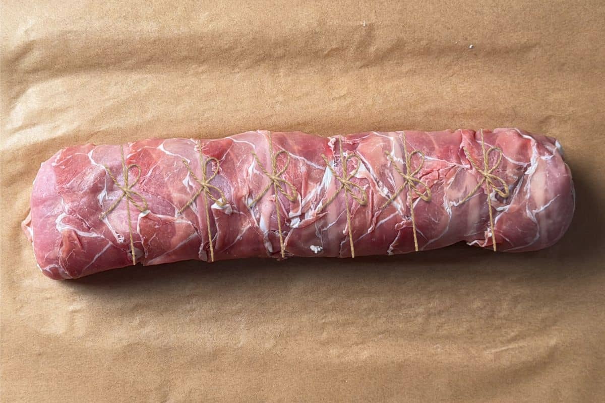 Tie the wrapped pork tenderloin with a piece of kitchen twine in five or six spots.