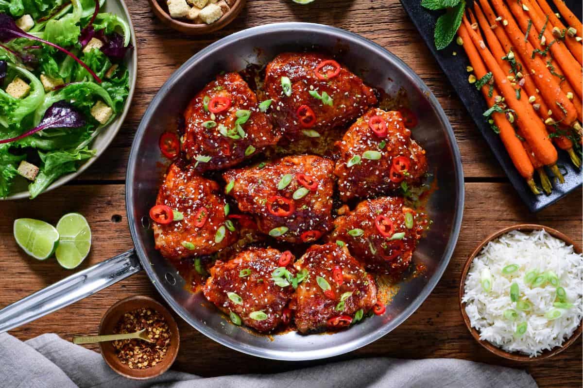Crispy Maple Gochujang Fire Chicken Thighs served with Spiced Honey-Roasted Carrots, a Simple Green Salad with Shallot Vinaigrette and rice.