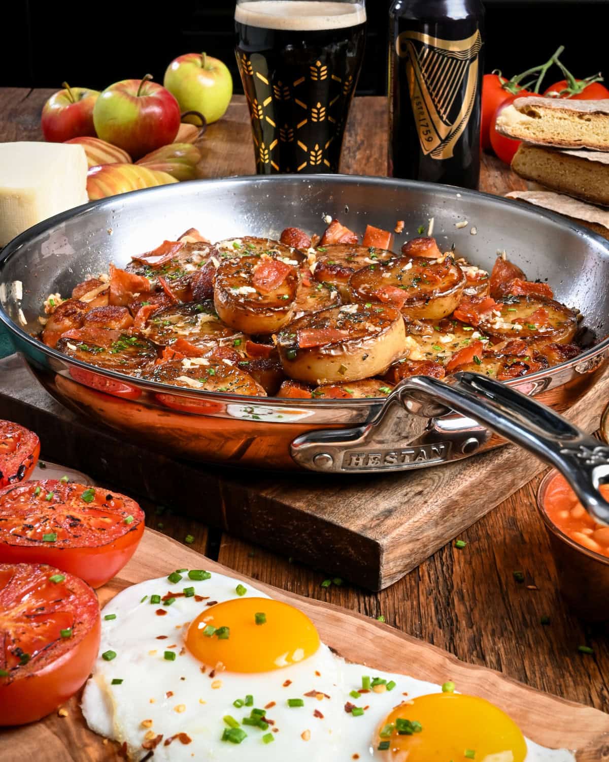 A crispy Irish Pub potato skillet with crispy potato rounds, sausage, bacon and served with sunnyside up eggs, roasted tomatoes and baked beans.