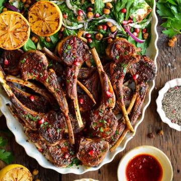 A platter half full with harissa lamb chops and the other half with a crispy chickpea & halloumi salad.