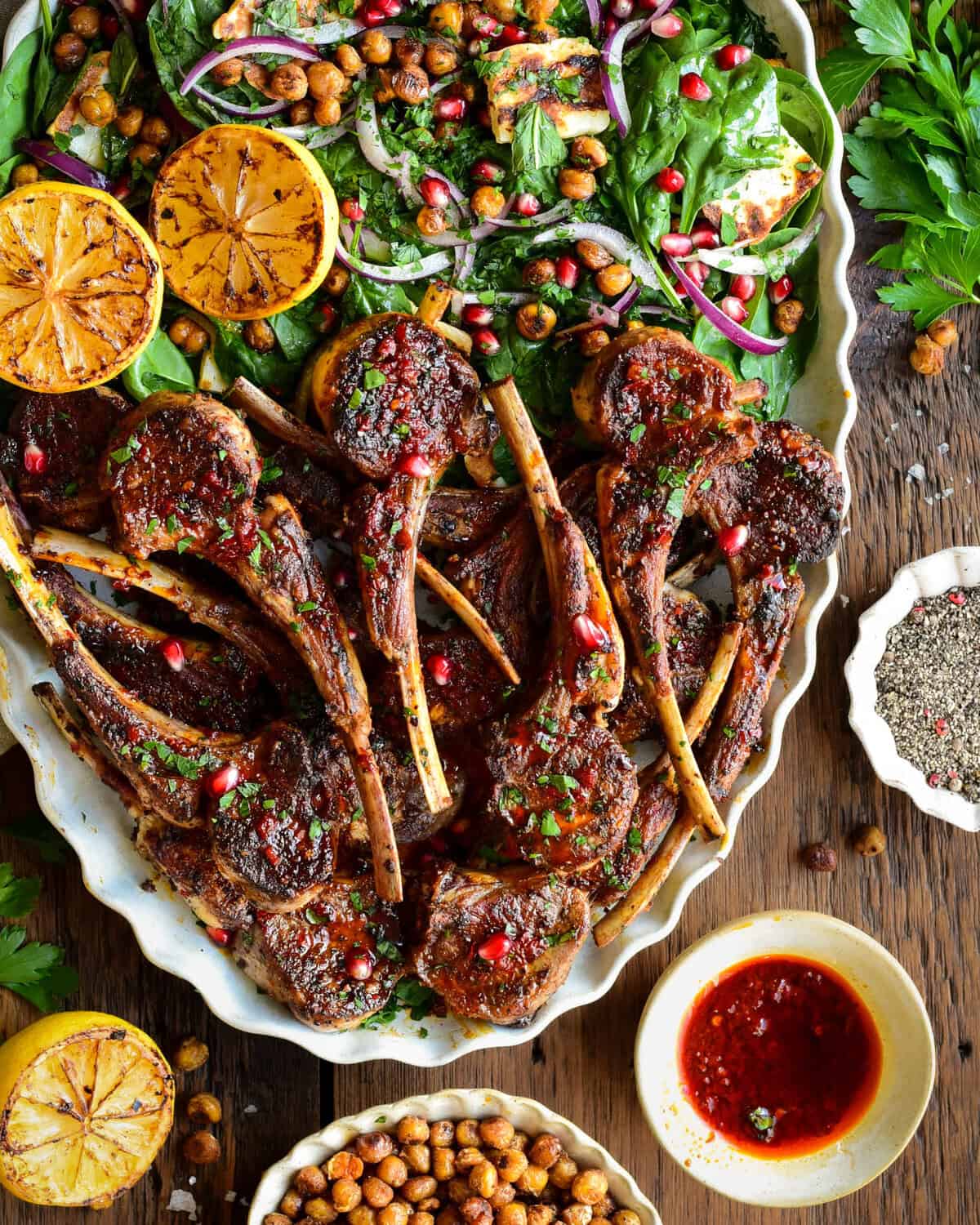 A platter half full with harissa lamb chops and the other half with a crispy chickpea & halloumi salad.