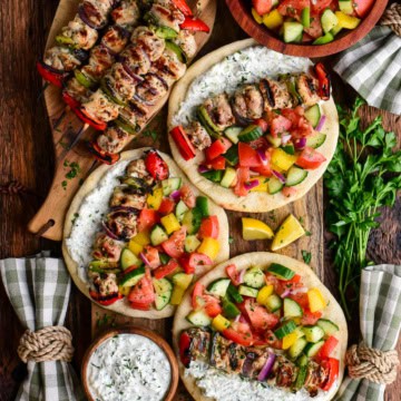 A pile of chicken souvlaki and three pitas loaded with chicken souvlaki, greenhouse salad and whipped feta tzatziki.