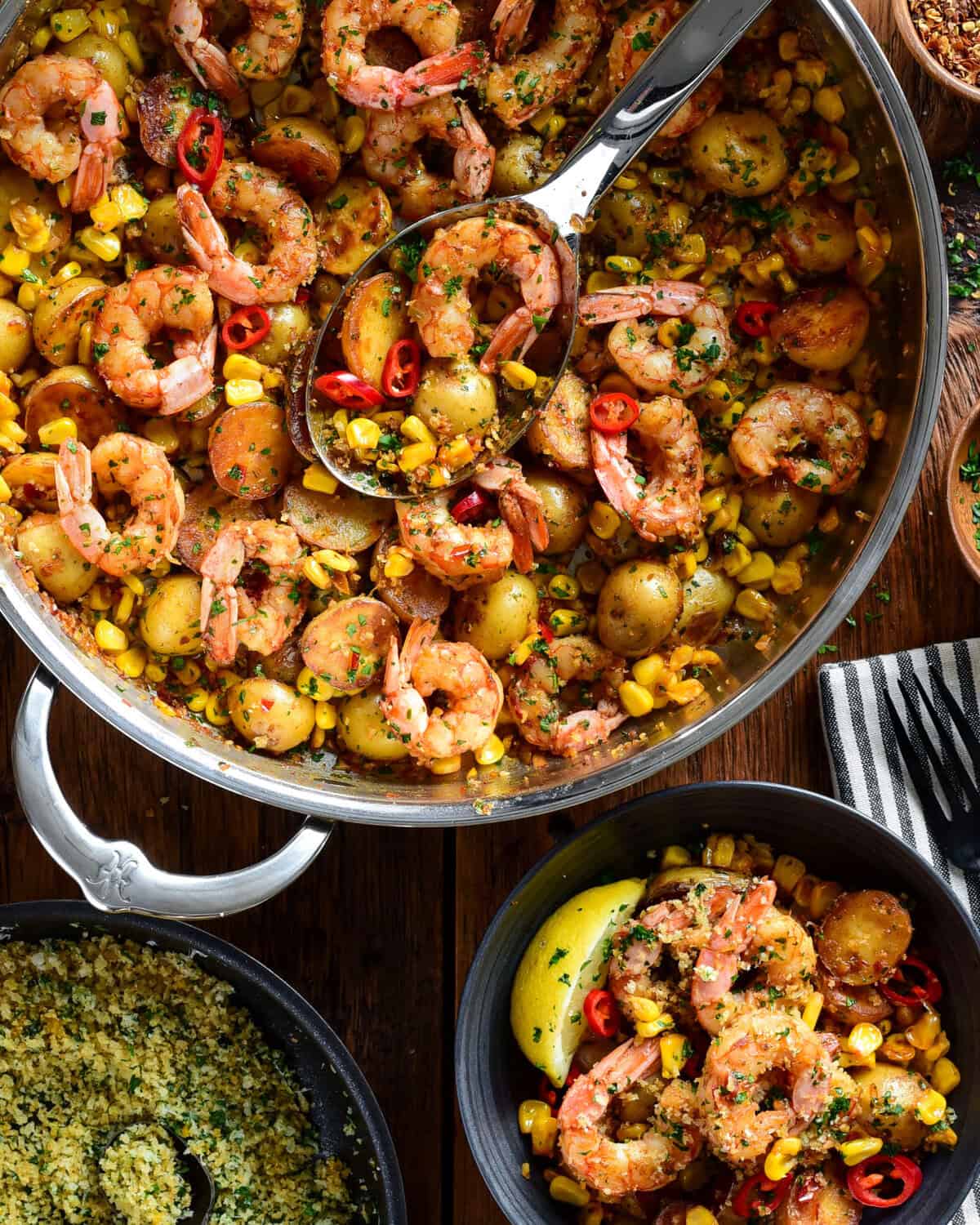 A skillet of spicy Calabrian shrimp with corn and potatoes. Served in a bowl with a lemon pangrattato sprinkled over it.