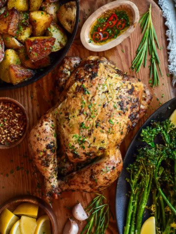 A whole rotisserie chicken served with golden duch fat potatoes and charred broccolini.