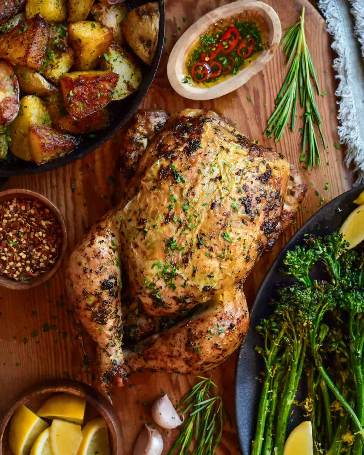 A whole rotisserie chicken served with golden duch fat potatoes and charred broccolini.