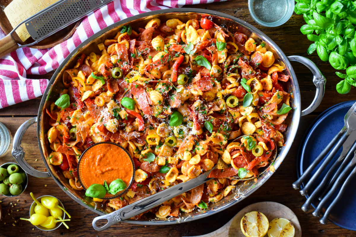 A large romesco pasta salad with spicy Italian meats, basil, olives, pickled peppers and fresh tomatoes.