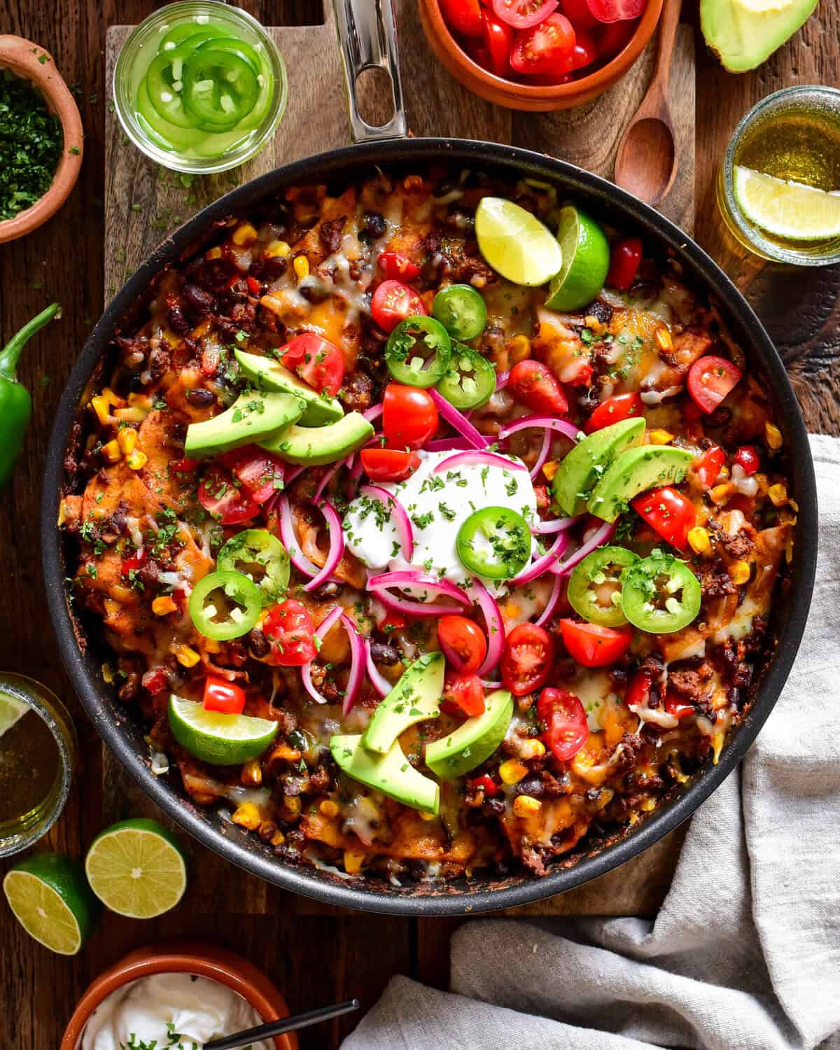 Fresh Mexican-style skillet with black beans, cherry tomatoes, avocado slices, red onions, and jalapeños garnished with lime wedges. Perfect for a flavourful, healthy meal or snack.