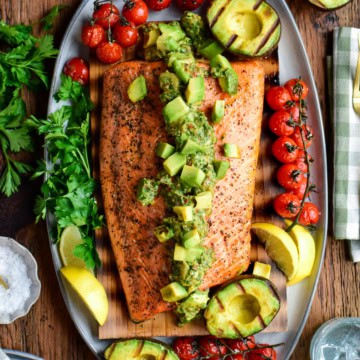 Cedar plank salmon topped with a smoky, chunky grilled avocado chimichurri salsa and charred tomatoes on the vine.