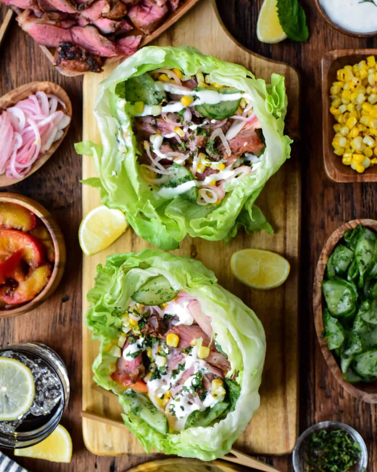 Fresh lettuce wraps with grilled lamb, vegetables, and flavorful sauces on a rustic wooden table. Perfect for healthy, delicious meals and meal prep.