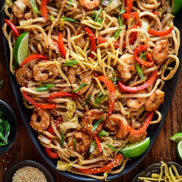 A platter of Sticky Soy Argentinian Shrimp & Fried Ginger Udon. Served with extra fried ginger, limes, sesame seeds and green onions.