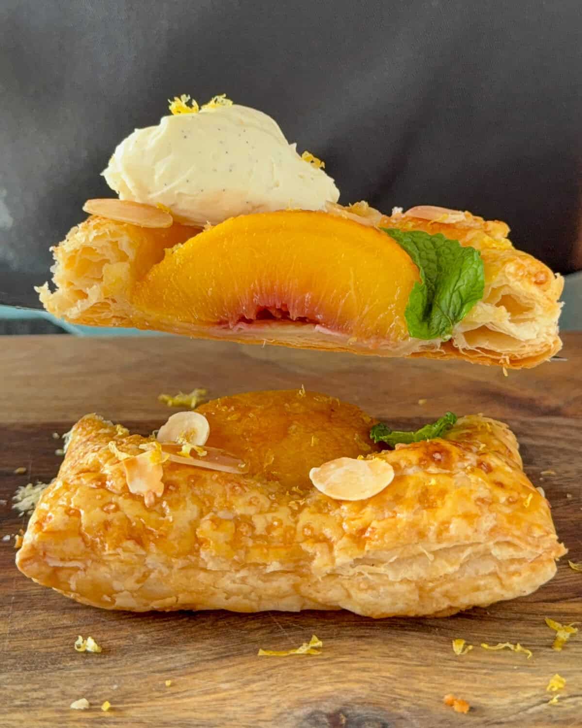 A cut cross-section of a hot honey peach puff pastry with mascarpone, mint and slivered almonds.