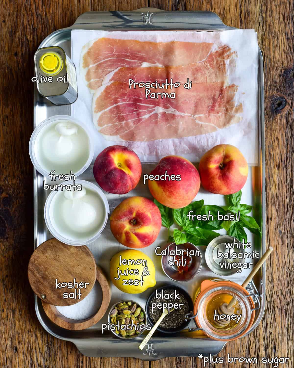 Ingredients are laid out on a tray and labelled. These ingredients are for a Seared Peaches with Burrata and Prosciutto recipe.