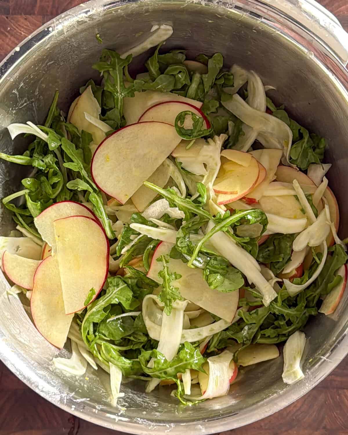 Toss the shaved apple and fennel salad in a bowl with a lemon Dijon vinaigrette.