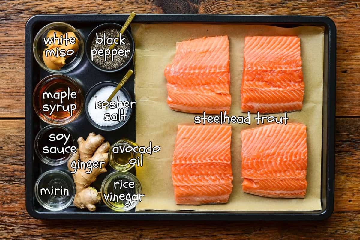 Ingredients laid out in a black sheet pan for a steelhead trout and a Miso-Maple glaze recipe.