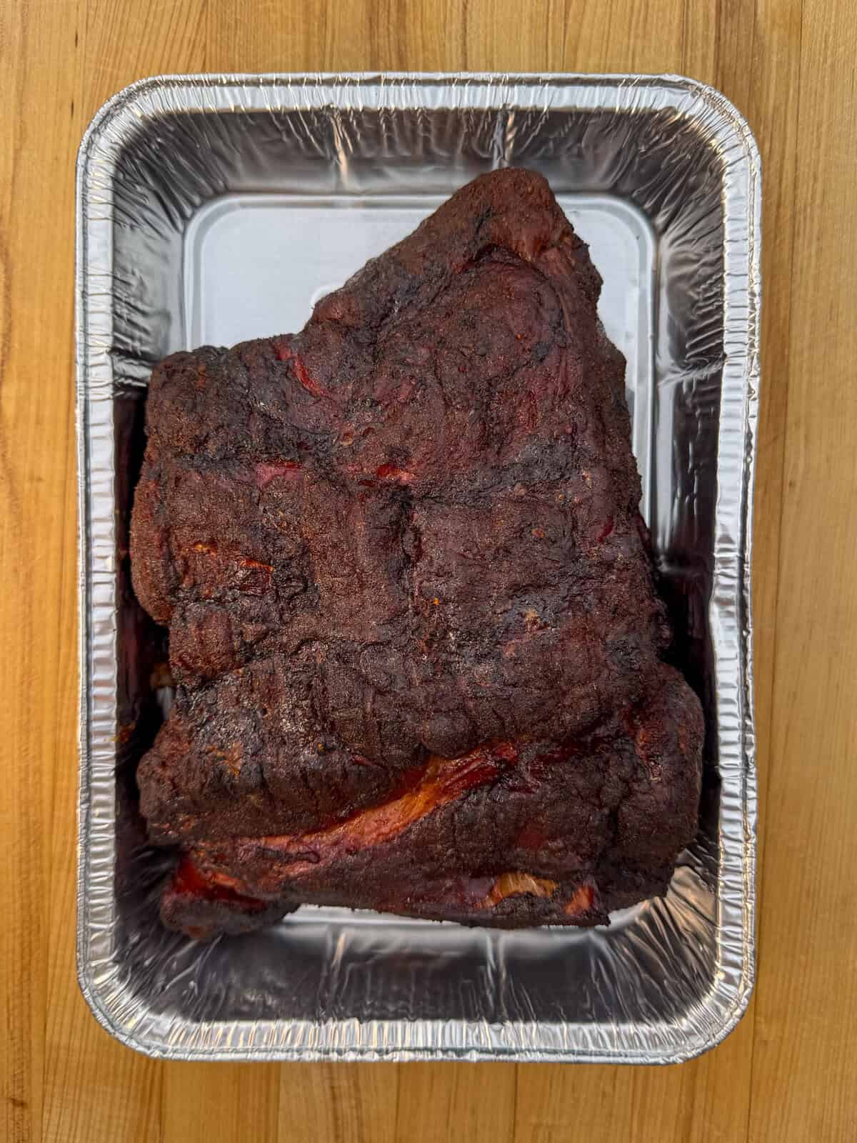 A cooked pork shoulder in a tray about to be shredded.