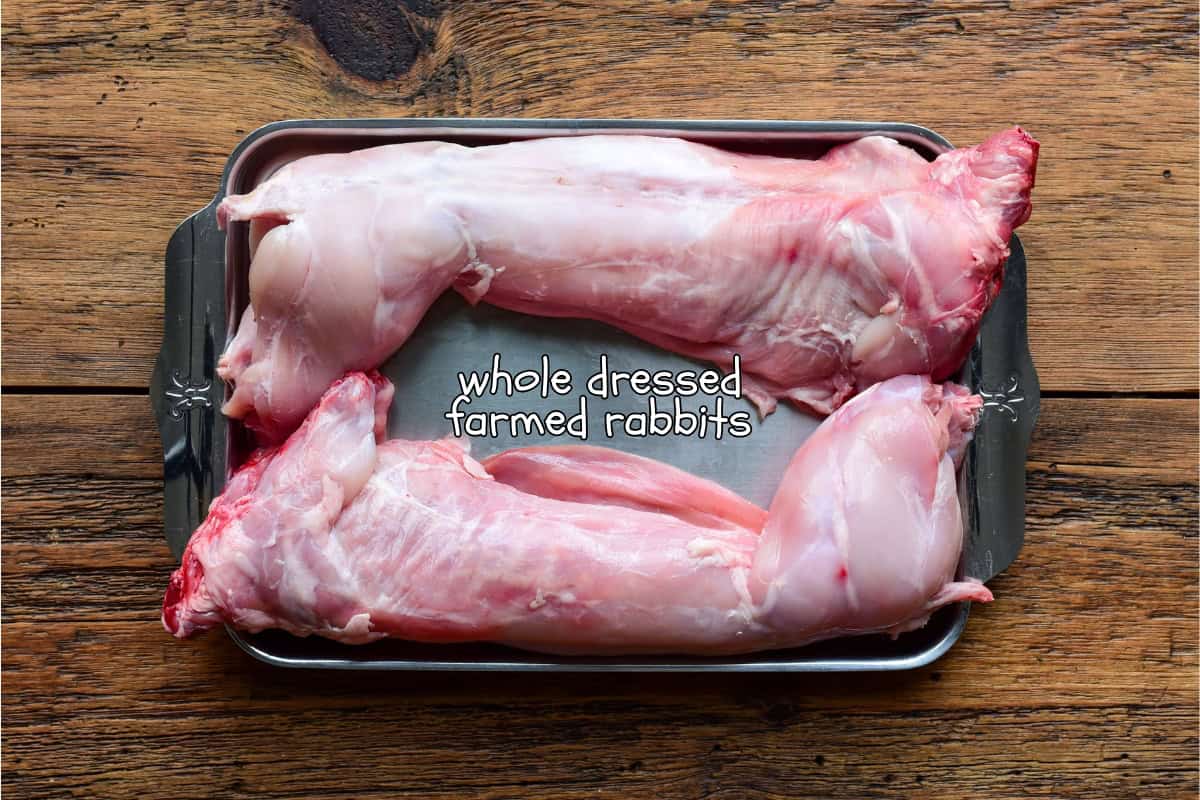 Two whole dressed farmed rabbits on a tray for a braised rabbit recipe.