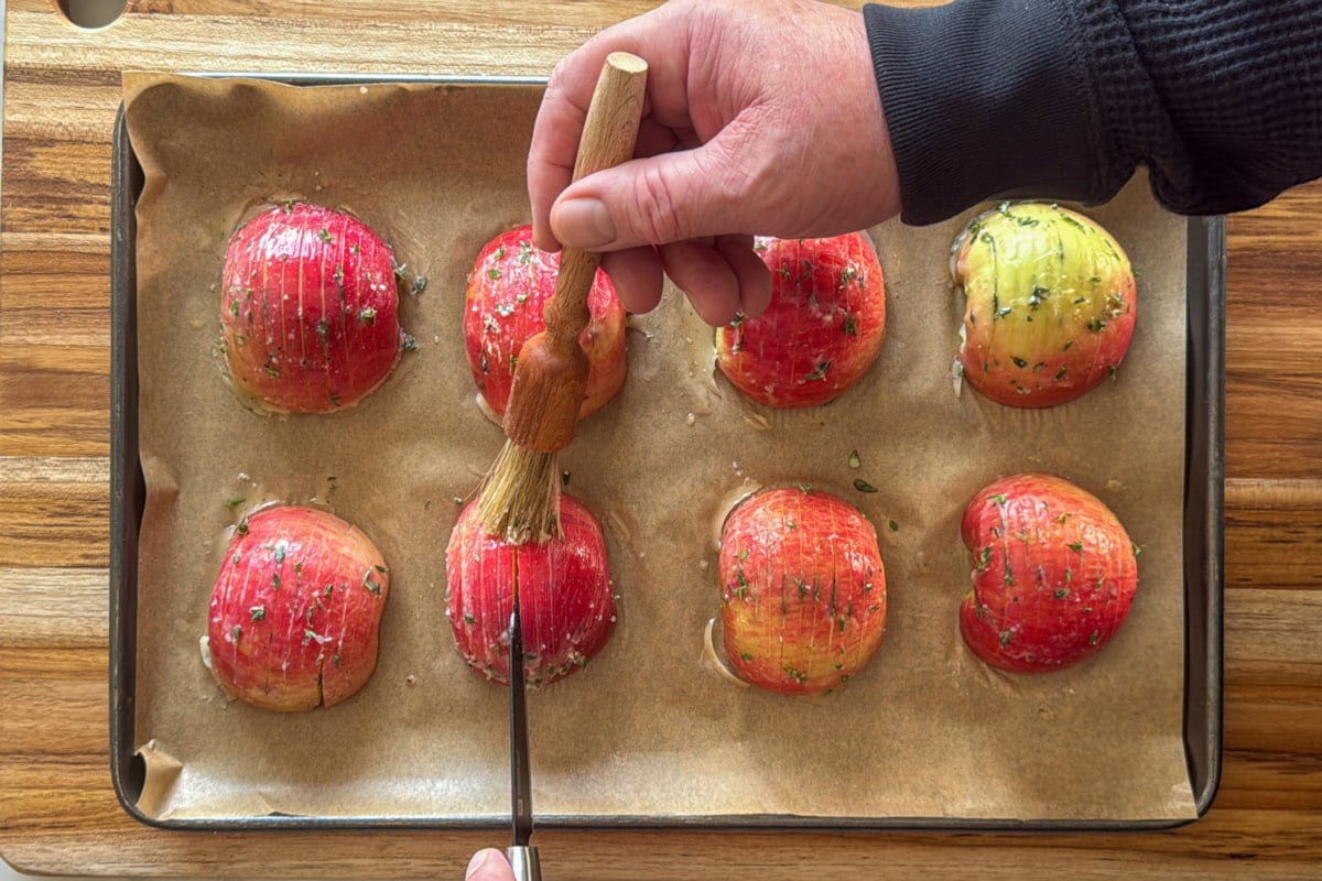 Brush the eight Hassleback apples with a butter herb mixture.