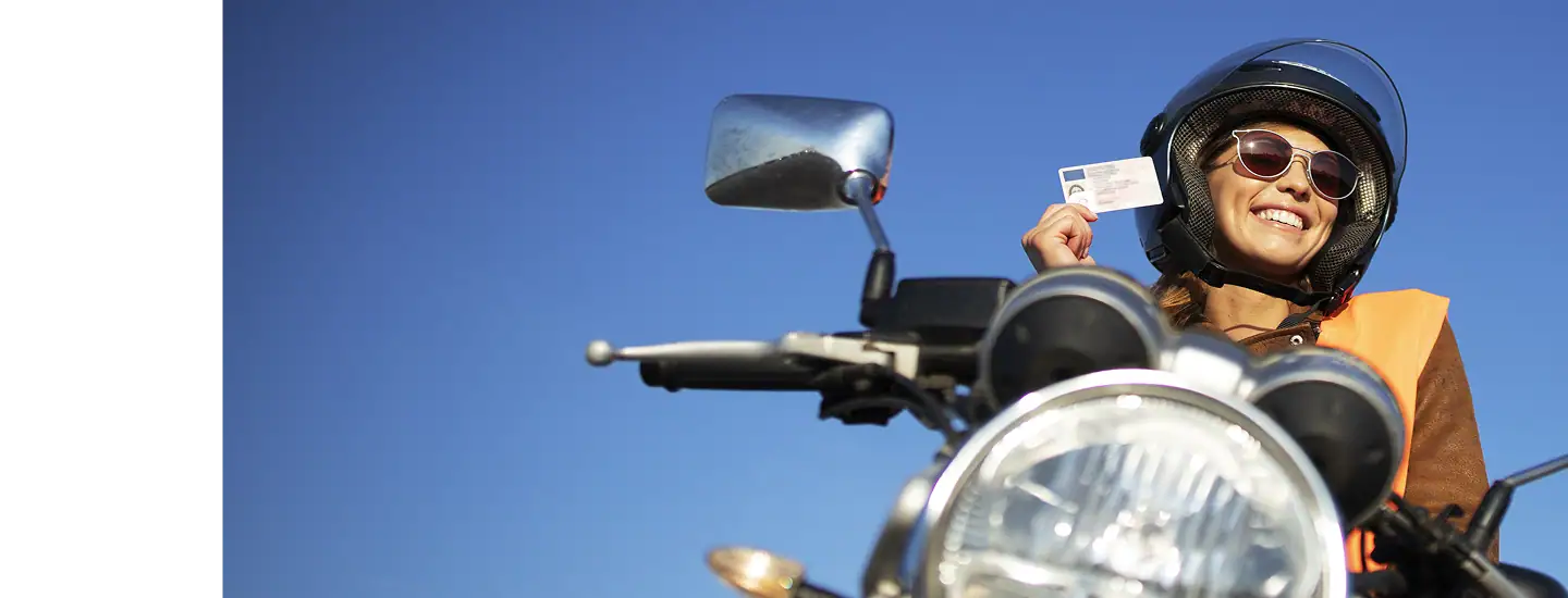 Altag Text nur: Frau fährt auf Motorrad, hält Führerschein in der Hand, lächelt bei schönem Wetter.