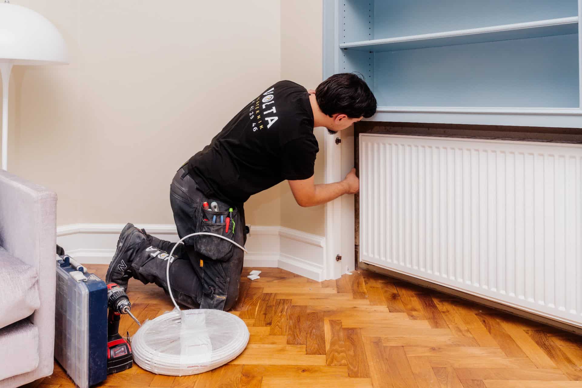 Autoriseret el installatør trækker kabel ved radiator for Volta El & Teknik