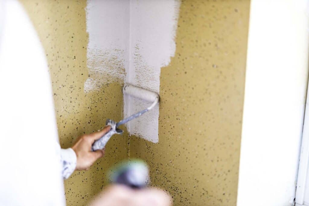 Renovering af vægge hvor hvid maling rulles over gammel farve