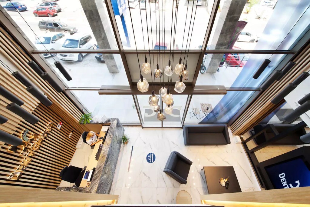 Vista dall'alto dell'ampia hall d'ingresso di una clinica DentGroup con lampadari di design e arredamento elegante