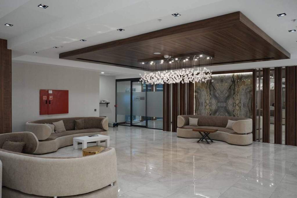 Intérieur de la clinique EsteCapelli Istanbul – accueil des patients dans un cadre élégant Hall d’accueil moderne de la clinique EsteCapelli à Istanbul avec canapés beiges et lustre design