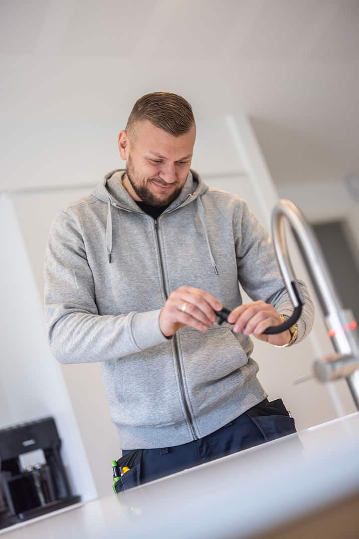 Portræt af autoriseret VVS installatør i grå trøje klar til opgave.
