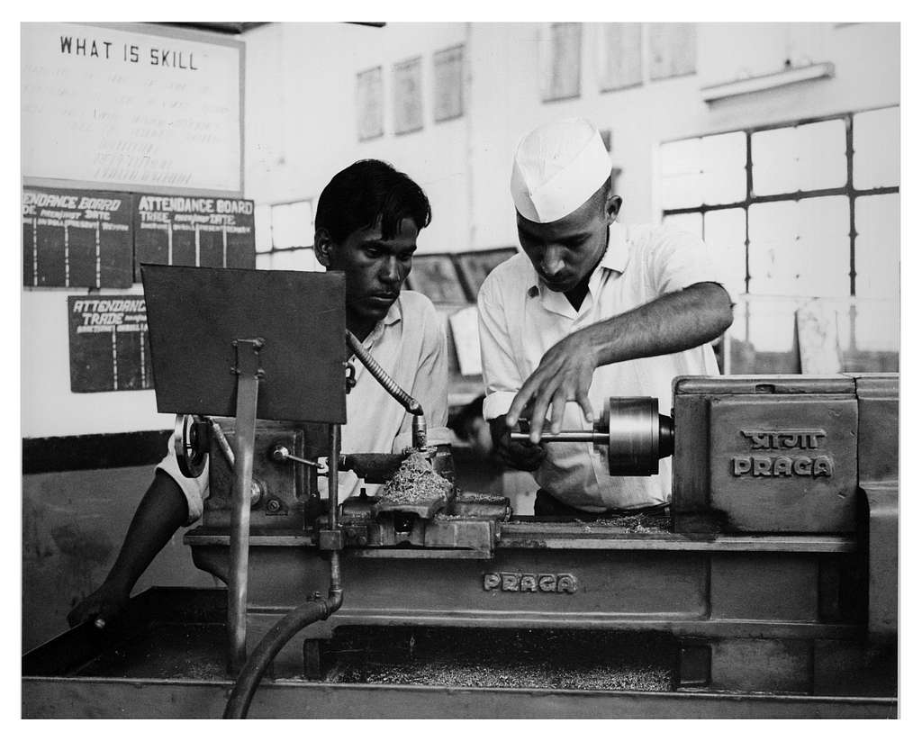 Skilled artisans working on precision metalturning lathe in a technical workshop.