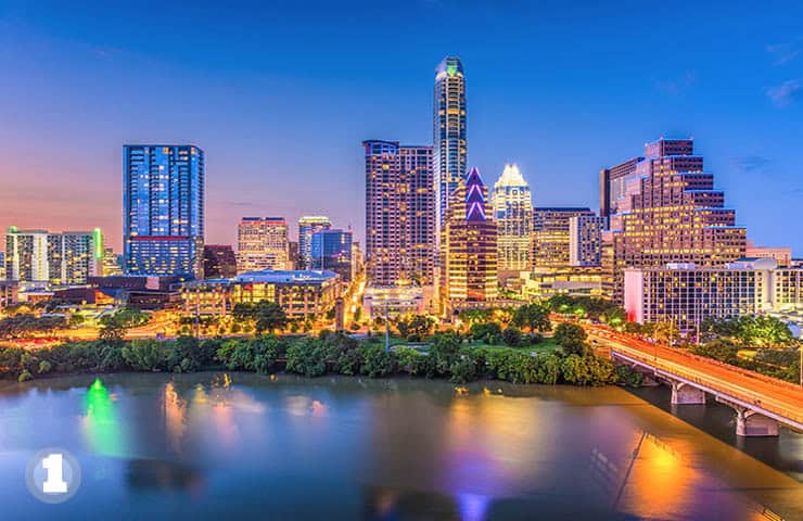 Vibrant Austin skyline with city lights reflecting on the lake at dusk, showcasing classical architecture and cityscape beauty.