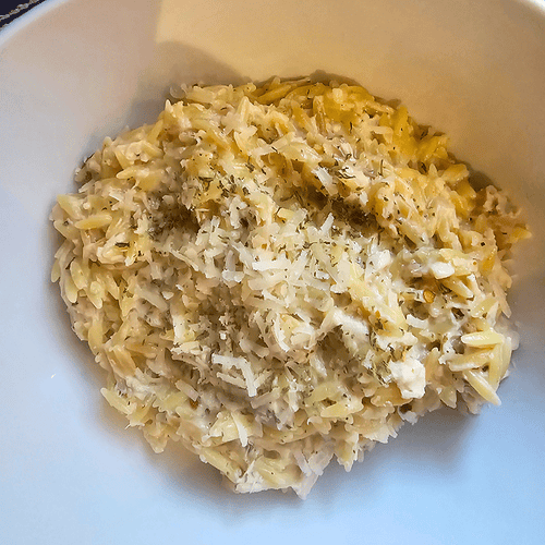 Creamy garlic Parmesan chicken with orzo pasta in a white bowl.