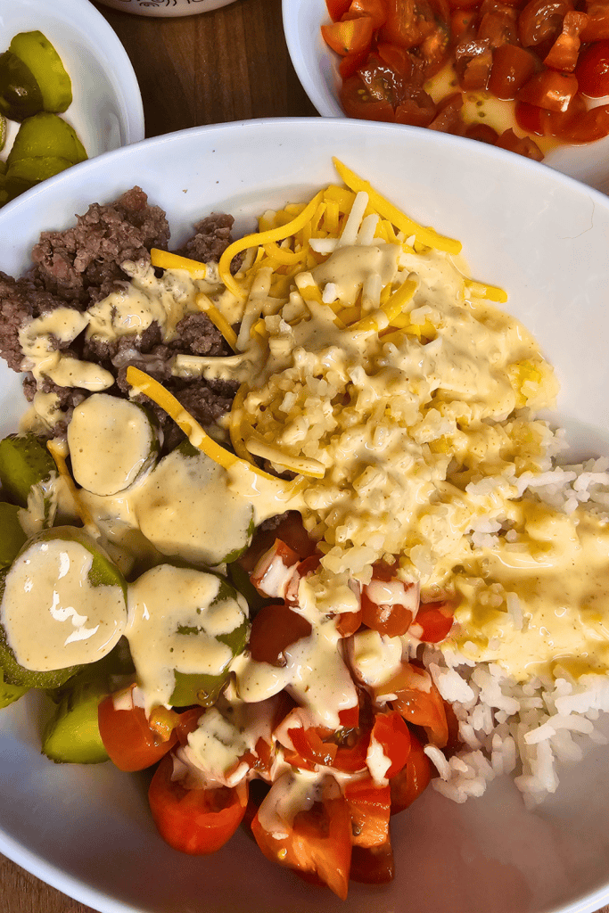 Delicious Big Mac-inspired rice bowl with seasoned beef, cheese, and fresh vegetables for a satisfyi.