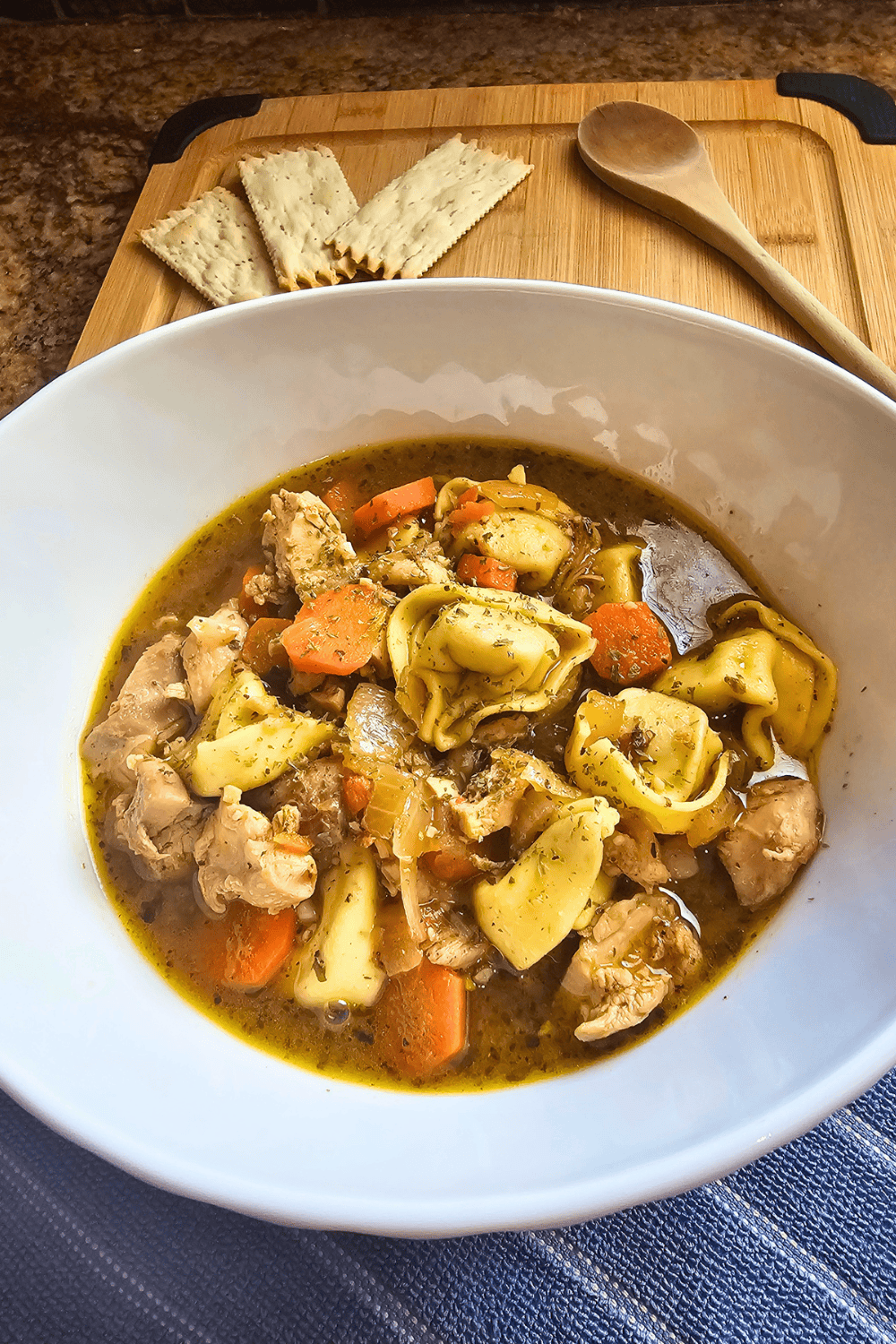 Hearty chicken tortellini soup with vegetables in a white bowl.