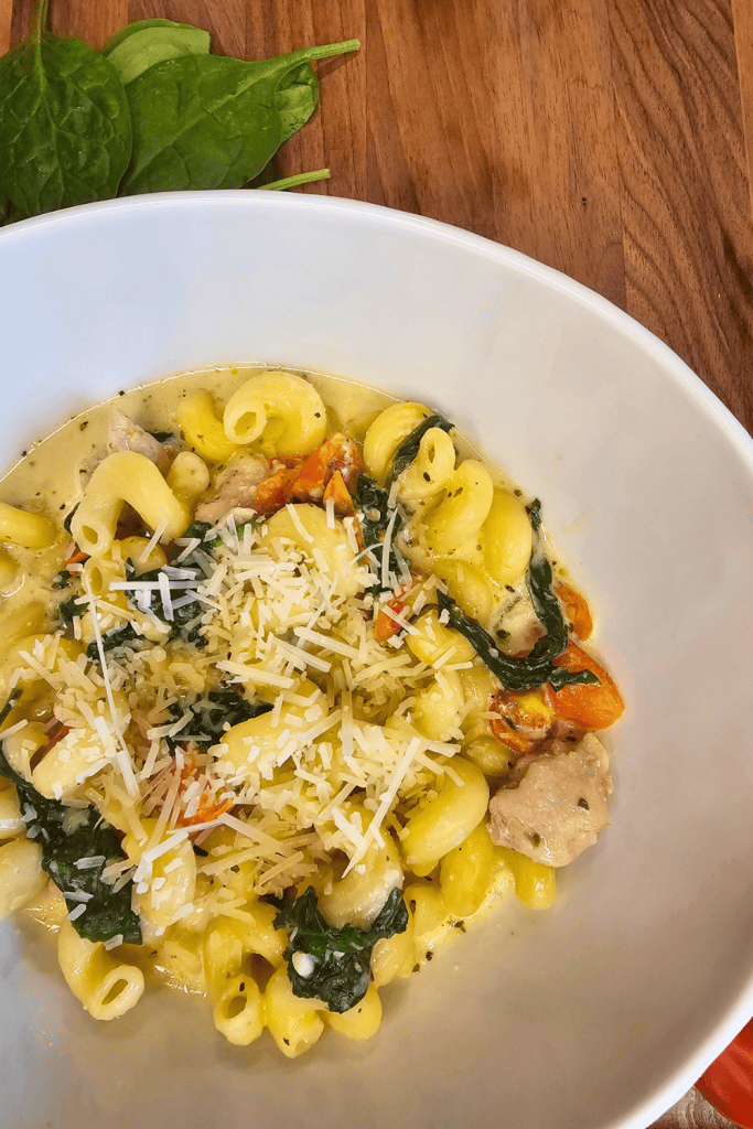 Delicious creamy garlic and herb tomato spinach pasta served in a white bowl, perfect for a comforti.