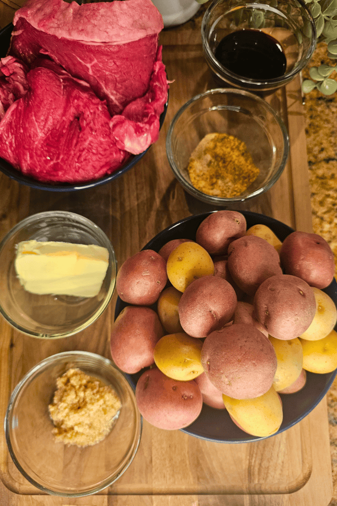 Fresh raw steak, potatoes, and seasonings for garlic butter steak dish.