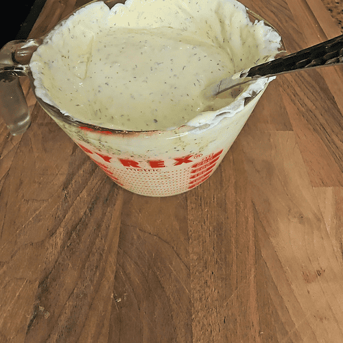 Herb-infused creamy dressing in a glass measuring cup, perfect for salads and bowls.