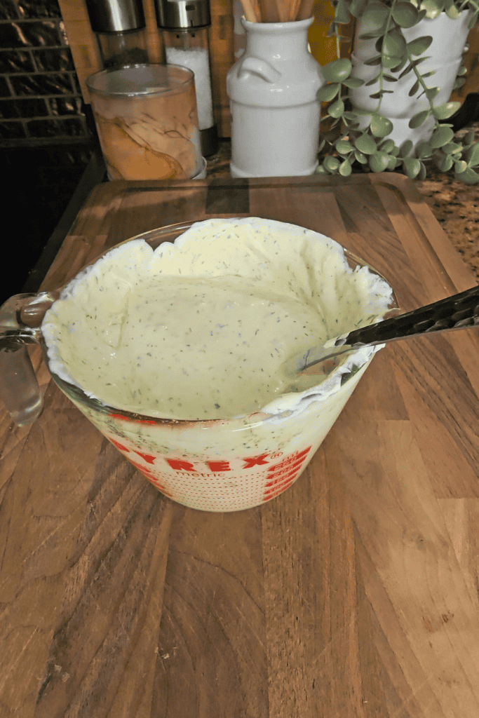 Herb-infused creamy dressing in a glass measuring cup, perfect for salads and bowls.