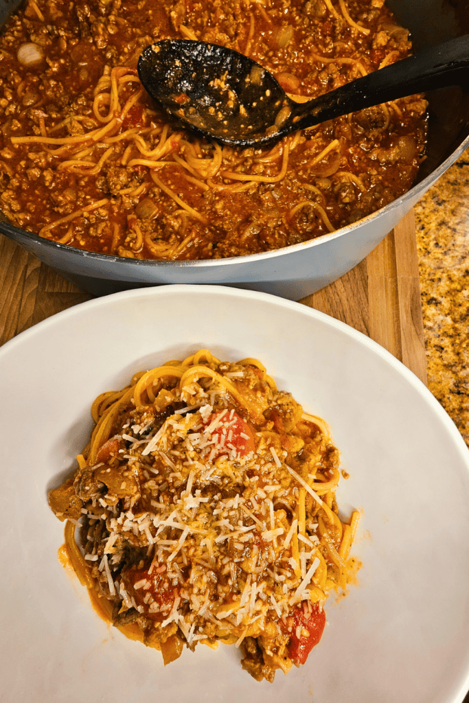 Delicious spaghetti with meat sauce and grated cheese in a white bowl.