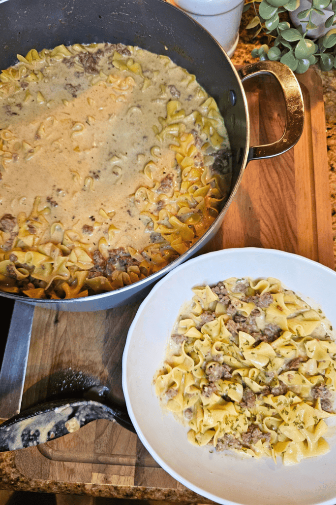 Creamy beef stroganoff with pasta in a skillet and bowl.