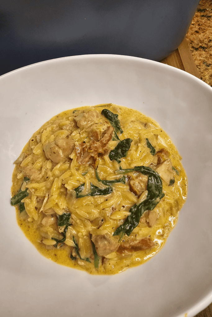 A bowl of Crockpot Marry Me Chicken Orzo sitting on the counter top.