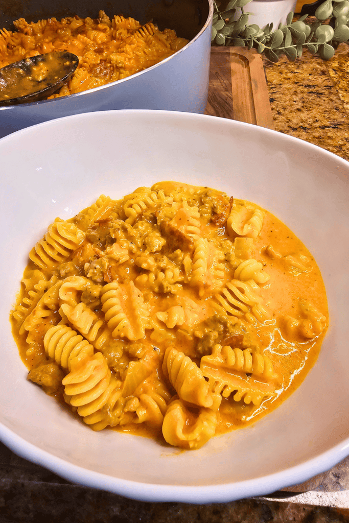 A close up picture of One Pan Cheesy Pizza Pasta dish in a white bowl on a counter top