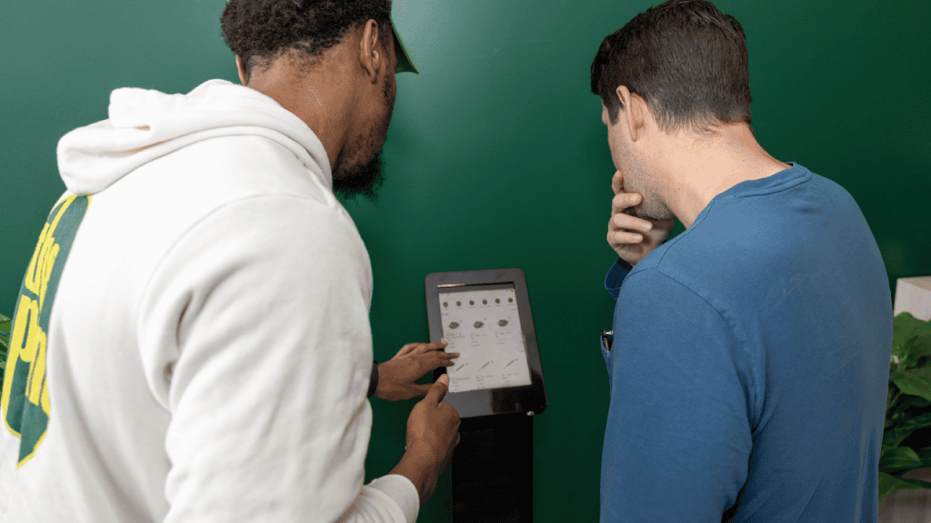 Staff assisting customer at kiosk to buy cannabis flower in New York