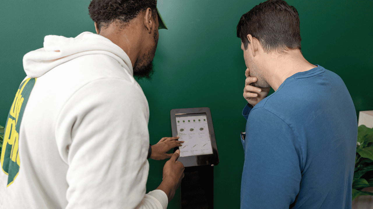 Staff assisting customer at kiosk to buy cannabis flower in New York