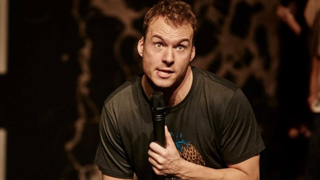 Komiker Simon Talbot på scenen med mikrofon