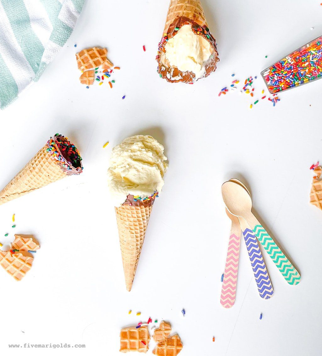 Marshmallow vanilla ice cream cones on white background with sprinkles and spoons